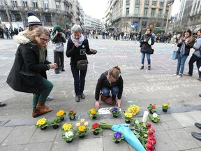 People leave messages and flowers in front of the stock exchange building in the city center of Brussels on following triple bomb attacks on March 22, 2016.  A series of apparently coordinated explosions ripped through Brussels airport and a metro train, killing at least 26 people in the latest attacks to target Europe.