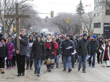 George Hind carries a cross as he and others march down 20th Street West during the Stations of the Cross, a walk which recalls the last hours of the Passion of Jesus, March 25, 2016.