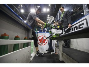 Cohyn Wells, 9, gets a fist pump from Rush transition/defender Adrian Sorichetti on the bench after Wells signed a one-day contract with the Saskatchewan Rush on Saturday, March 26th, 2016. Cohyn Wells is the Saskatchewan representative for the Children's Miracle Network's Champion Program.(Liam Richards/Saskatoon StarPhoenix)