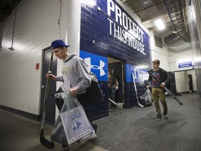 Mason McCarty, left, and Wyatt Slboshan, right, carries their bags and sticks as members of the Saskatoon Blades clean out their lockers for the season on Monday