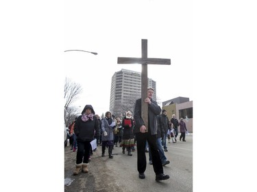 George Hind carries a cross, as he and others march down 20th Street West during the Stations of the Cross, a walk which recalls the last hours of the Passion of Jesus, on Friday, March 25th, 2016.
