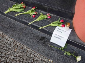 A man looks at flowers and a sign reading (Defy terror, protect freedom) outside the Belgium embassy in Berlin on March 22, 2016.