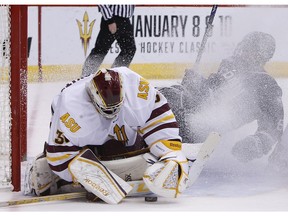 Arizona State goalie Ryland Pashovitz, left, makes a save against Connecticut defenseman Johnny Austin during the second period of an NCAA college game at the Desert Hockey Classic tournament on Jan. 10, 2016, in Glendale, Ariz.