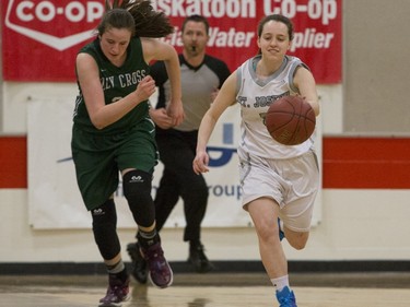 Holy Cross Crusaders' Kyla Shand (L) runs after St. Joseph Guardians' Megan Wist as she moves the ball in the girls high school basketball city final at Bedford Road Collegiate, March 12, 2016.