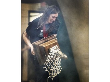 Sure-handed CIS women's University of Saskatchewan Huskies all-star basketball player Dalyce Emmerson almost drops the bronze baby trophy but recovers nicely before gracefully draping the winner's net around her and carrying the championship hardware into a rally in the PAC Gym,  March 23, 2016.