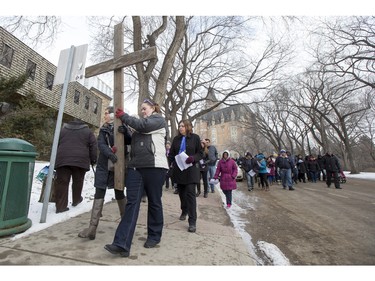 People march and carry a cross down 20th Street West during the Stations of the Cross, a walk which recalls the last hours of the Passion of Jesus, on Friday, March 25th, 2016.