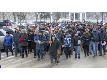 People march and carry a cross down 20th Street West during the Stations of the Cross, a walk which recalls the last hours of the Passion of Jesus, on Friday, March 25th, 2016.