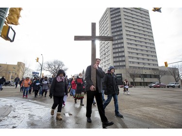 George Hind carries a cross, as he and others march down 20th Street West during the Stations of the Cross, a walk which recalls the last hours of the Passion of Jesus, on Friday, March 25th, 2016.