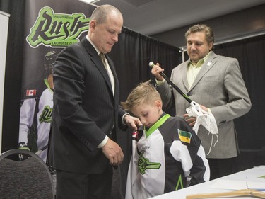 Saskatchewan Rush captain Chris Corbeil (not shown), nine-year-old Cohyn Wells (C) and Rush head coach and general manager Derek Keenan (L) hold a press conference for the signing of a one-day contract of Cohyn to the Saskatchewan Rush, March 26, 2016. Wells is the Saskatchewan representative for the Children's Miracle Network's Champion Program.