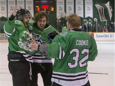 University of Saskatchewan Huskies forward Matthew Spafford and forward John Lawrence, and goalie Jordon Cooke, right, celebrate after defeating the University of Alberta Golden Bears to win the CIS Men's Hockey Canada West championship on March 5, 2016.