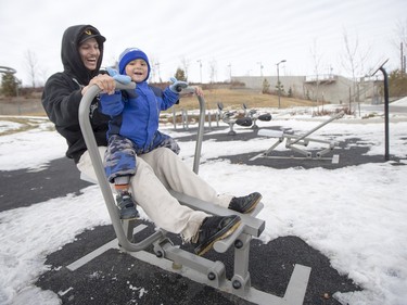 Darnel Sangrias and his two-year-old son Dylan take advantage of the warm weather to test out the gym equipment at River Landing in Saskatoon, March 6, 2016.