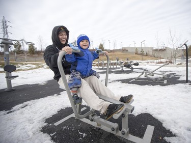 Darnel Sangrias and his two-year-old son Dylan take advantage of the warm weather to test out the gym equipment at River Landing in Saskatoon, March 6, 2016.