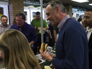 Saskatchewan Party candidate Don Morgan waits in line for a burger after the revealing of the Saskatchewan Party platform at their Southeast campaign office in Saskatoon, March 19, 2016.