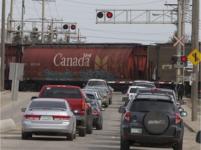 People and vehicles wait for a train to cross Central Avenue in Sutherland Tuesday, April 22, 2014.