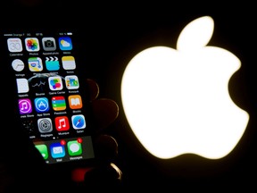 (FILES) This file photo taken on January 30, 2015 shows an illustration of an iPhone held up in front of the Apple Inc. logo in Lille, France.