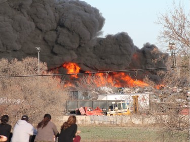 A crowd gathered to watch firefighters battle a blaze at an auto salvage yard at Avenue P and 14th Street West in Saskatoon on April 19, 2016.