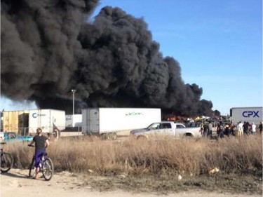 A crowd gathered to watch firefighters battle a blaze at an auto salvage yard at Avenue P and 14th Street West in Saskatoon on April 19, 2016.