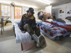 Terrence Bird, a client of the Scattered Site Outreach Program, takes off his boots before going to sleep on a lawn chairs for the night on Thursday, April 21st, 2016.