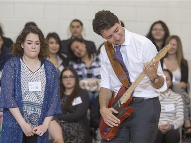 Prime Minister Justin Trudeau strums this hand crafted guitar built by students and given to him as a gift during his visit at Oskayak High School in Saskatoon, April 27, 2016.