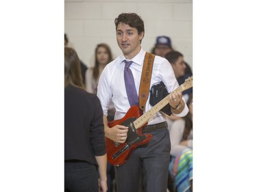 Prime Minister Justin Trudeau strums this hand crafted guitar built by students and given to him as a gift during his visit at Oskayak High School in Saskatoon, April 27, 2016.