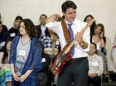Prime Minister Justin Trudeau tries on this hand crafted guitar built by students and given to him as a gift during his visit at Oskayak High School in Saskatoon, April 27, 2016.