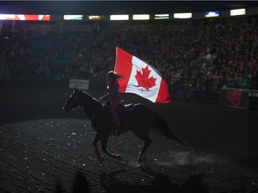 A women rides a horse carrying the Canadian flag during the opening ceremonies of the Saskatoon Summer Rodeo at SaskTel Centre in Saskatoon, April 23, 2016.