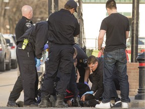 A man receives aid from EMS at the corner of 10th Street East and Broadway Avenue after a report of a male being assaulted at the location, Monday, April 25, 2016.