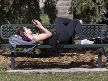 Rebecca Zakreski enjoys the sunshine on a bench with some phone reading in Friendship Park, April 28, 2016.