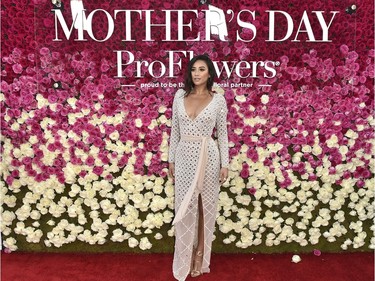 Shay Mitchell poses in front of the ProFlowers floral wall, featuring 2,500 dazzling pink and white roses, at the "Mother's Day" premiere at the TCL Chinese Theatre, April 13, 2016 in Hollywood, California.