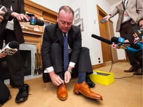 Kevin Doherty, Saskatchewan's minister of finance, puts on new shoes during a pre-budget Day photo opportunity at the Legislative Building in Regina, Saskatchewan on Tuesday May 31, 2016. Doherty will reveal the province's budget Wednesday, which is expected to include spending cuts.