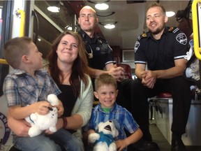 Aiden Warren, left, with his mother Samantha and twin brother Kayden, meet paramedics Luc Duval and Tom Barbier, who helped when Warren went into labour on Highway 16.