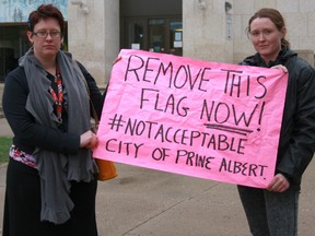 Lana Wilson and Emma Anderson hold up a sign in front of Prince Albert's City Hall protesting the city’s decision to raise a Celebrate Life Flag