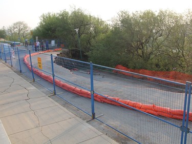 Residents can be seen on the outsides of a fence that circles a massive sinkhole on Saskatchewan Crescent East on Thursday, May 5, 2016. City officials are set to provide an update on the slope failure on Friday morning.(Morgan Modjeski/The Saskatoon StarPhoenix)