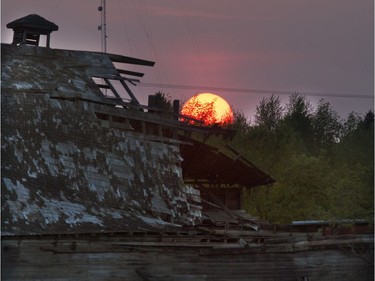 Smoke in the sky from forest fires gives the setting  sun more of a red glow east of Saskatoon near an old decrepit barn, May 17, 2016.
