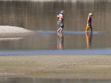 A couple and their child waded through the water back to their kayak from a secluded sandbar under the South Bridge for some sand and sun during above normal temperatures in Saskatoon today and for the coming week, Monday, May 2.