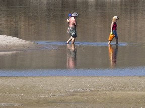 A couple and their child waded through the water back to their kayaked from a secluded sandbar under the South Bridge for some sand and sun on May 2, 2016.
