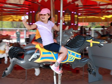 Six-year-old Shayna Bloom waves at her dad while riding the carousel on opening day at Kinsmen Park on May 8, 2016.