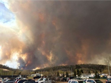 Smoke fills the air near a parking lot in Fort McMurray, Alberta, May 3, 2016 in this image provide by radio station CAOS91.1. At least half of the city of Fort McMurray in northern Alberta was under an evacuation notice Tuesday as a wildfire whipped by winds engulfed homes and sent ash raining down on residents.
