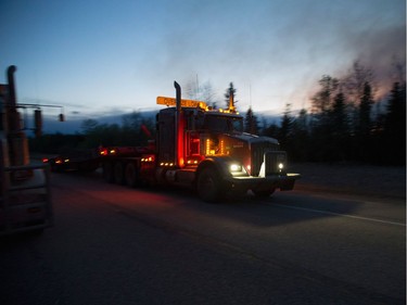 A truck carrying firefighting supplies drives past smoke from a nearby fire on May 5, 2016 near of Fort McMurray, Alberta. Wildfires, which are still burning out of control, have forced the evacuation of more than 80,000 residents from the town.