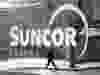 A pedestrian is reflected in a Suncor Energy sign in Calgary.