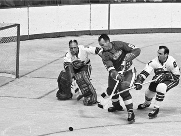 In this Oct. 26, 1967 file photo, California Seals goalie Charlie Hodge (L) knocks the puck away as Detroit Red Wings star Gordie Howe tries a shot on goal as the Seals' Bob Baun comes in at right during the second period of an NHL hockey game in Detroit.