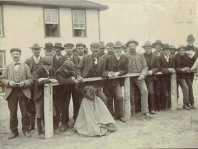 According to the book The Face Pullers: Photographing Native Canadians, this 1906 photograph of a First Nations man, white settlers looming enigmatically over him, was taken by Ralph Dill, Saskatoon’s first photographer.