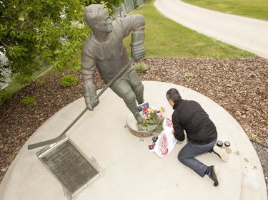 Saskatoon Blades president Steve Hogle places pucks and jerseys at the Gordie Howe statue outside of Sasktel Centre in Saskatoon, June 10, 2016. Howe passed away today at the age of 88.