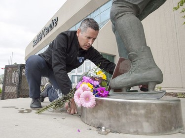 Saskatoon Blades president Steve Hogle places pucks and jerseys at the Gordie Howe statue outside of Sasktel Centre in Saskatoon, June 10, 2016. Howe passed away today at the age of 88.