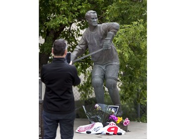 Flowers, jerseys, pucks and pictures lay next to the skates of the statue of Gordie Howe at SaskTel Centre in Saskatoon, where the WHL's Saskatoon Blades president Steve Hogal takes a photo, June 10, 2016.