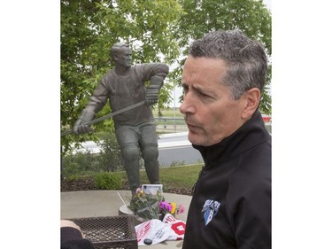 Flowers, jerseys, pucks and pictures lay next to the skates of the statue of Gordie Howe at SaskTel Centre in Saskatoon, where the WHL's Saskatoon Blades president Steve Hogal takes a photo and speaks to the media, June 10, 2016.