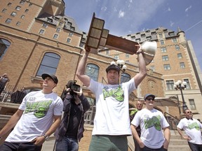 Saskatchewan Rush sniper Mark Matthews, flanked by teammates Nik Bilic and Robert Church, hoists the Champion's Cup during a Tuesday rally in downtown Saskatoon.