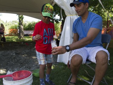 Ninad (L) and his father play at the Fossil Find both at the PotashCorp Saskatchewan Children's Festival in Kiwanis Park in Saskatoon, June 4, 2016.