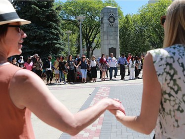 Residents of Saskatoon share a round circle dance during World Refugee Day put on by the Saskatoon Refugee Coalition at Civic Square at City Hall in Saskatoon on June 20, 2016.