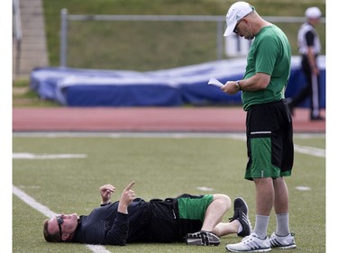 Head coach Chris Jones gives instructions while stretching out on the ground during Rider training camp at Griffiths Stadium in Saskatoon, Friday, June 03, 2016.